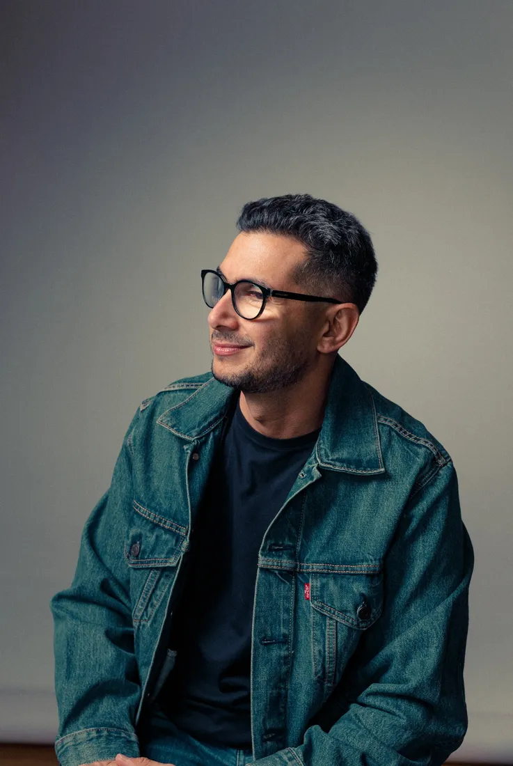 Salim Khouri usando jaqueta jeans e óculos em retrato editorial.